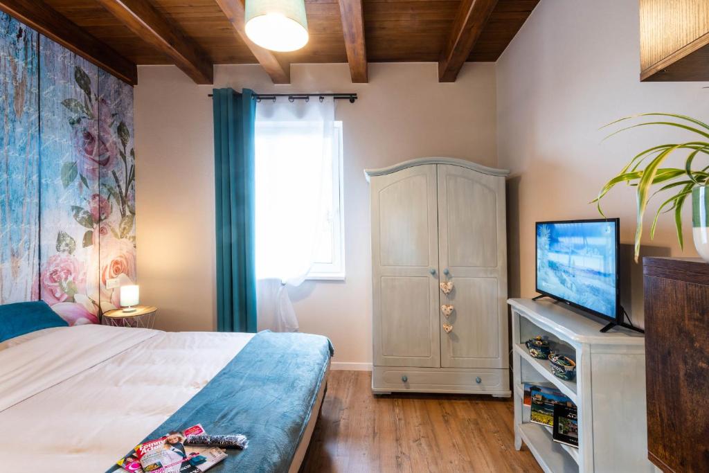 a bedroom with a bed and a flat screen tv at Gîtes Au fil des saisons proximité EUROPA PARK in Diebolsheim