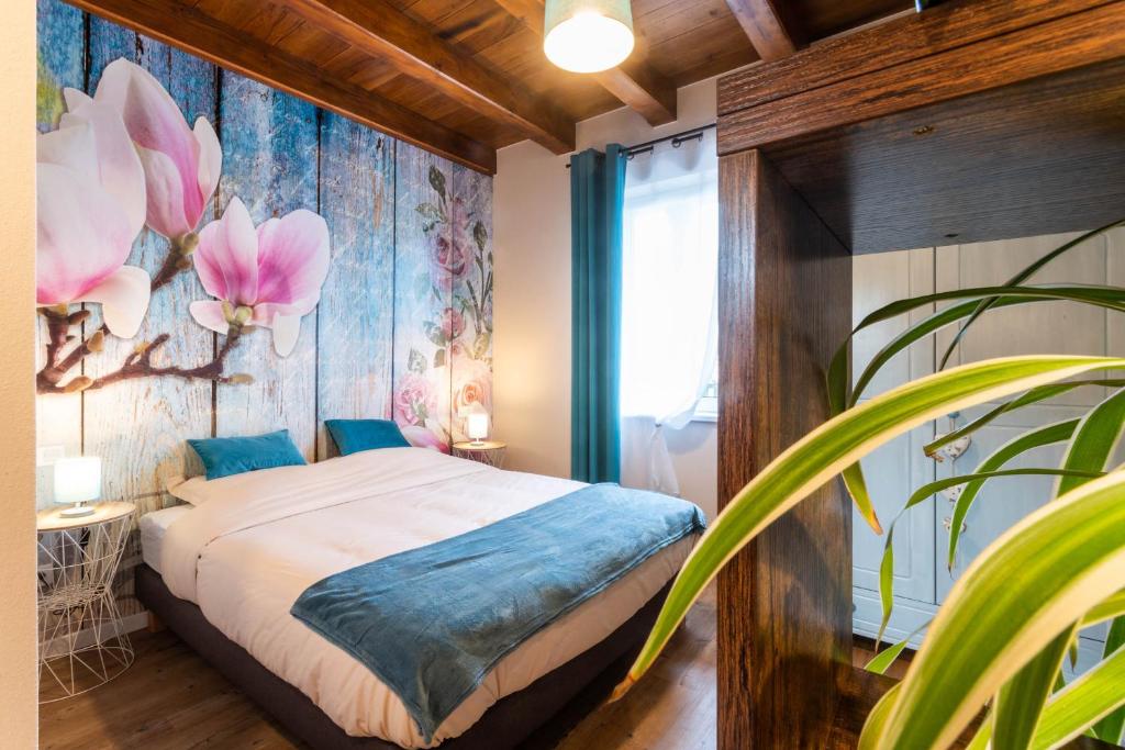 a bedroom with a bed with a flower mural on the wall at Gîtes Au fil des saisons proximité EUROPA PARK in Diebolsheim