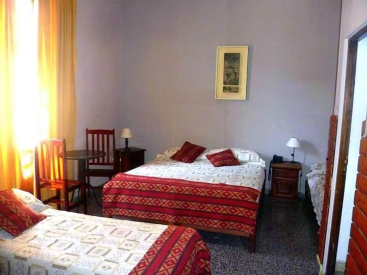 a hotel room with two beds and a table at Hotel inty raimi in Salta