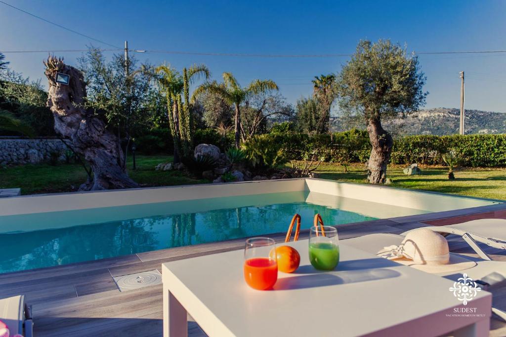a white table with drinks on it next to a swimming pool at Villa Clara Country Retreat in Solarino