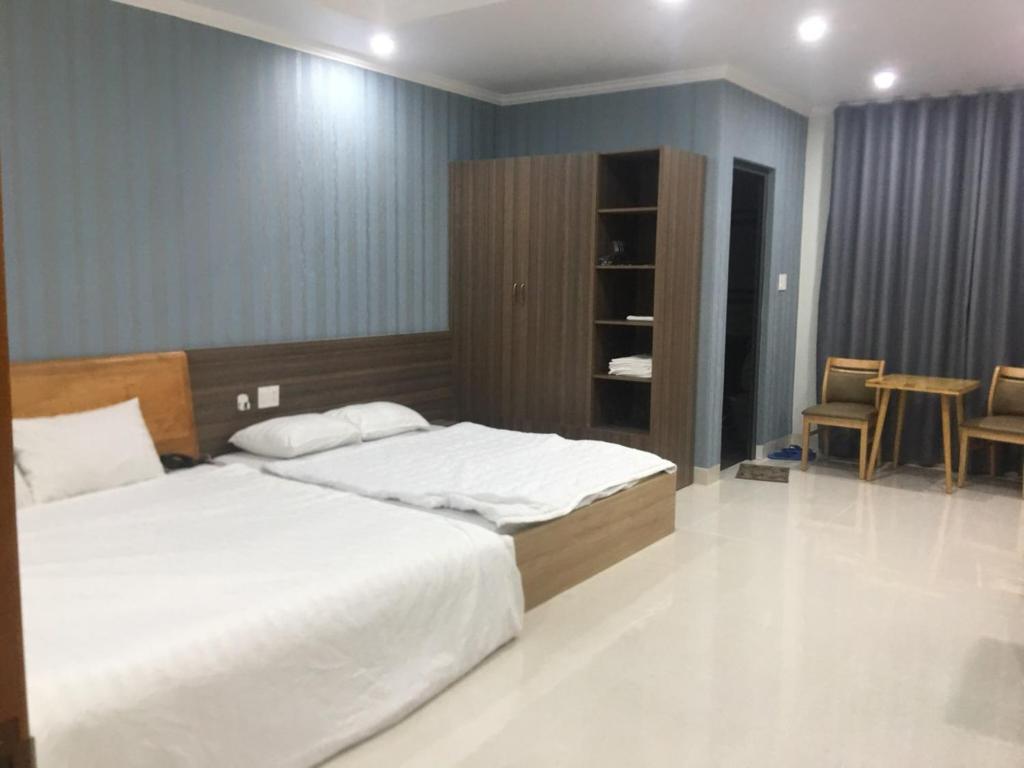 頭頓的住宿－Nhat Thu Hotel & Apartment，一间卧室配有两张床和一张桌子及椅子