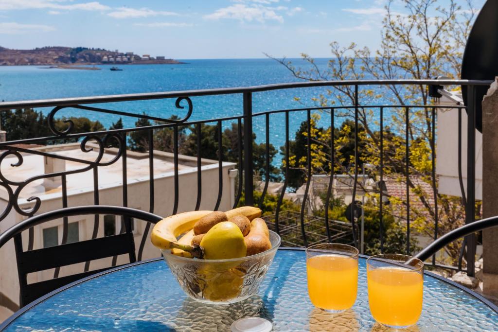 uma mesa com uma taça de fruta e dois copos de sumo de laranja em Altea em Šušanj