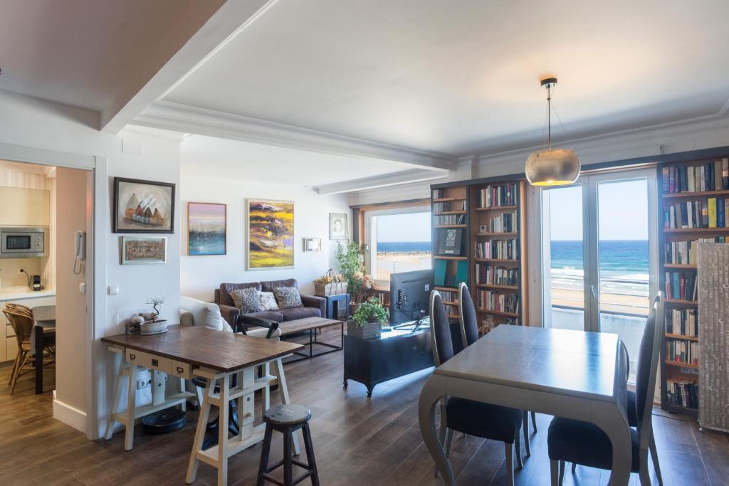 a living room with a table and a dining room with the ocean at Colon Zurriola IB Apartments in San Sebastián