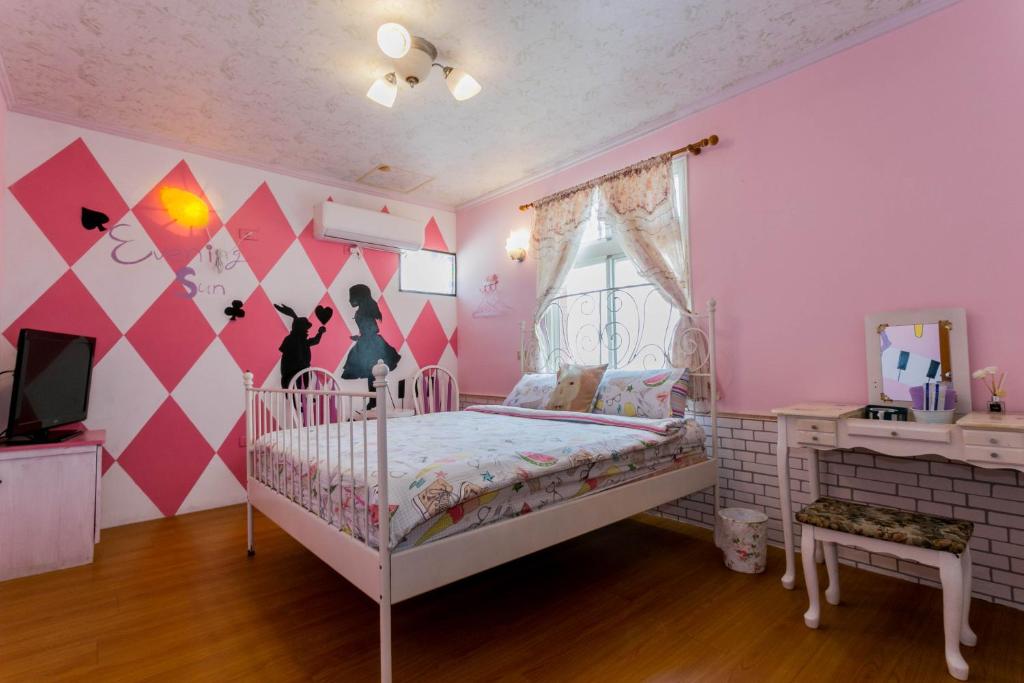 緑島郷にあるイブニング サン B＆Bのピンクルームのベッドルーム1室(白いベビーベッド付)