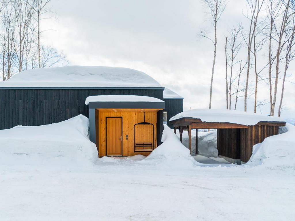 新雪谷的住宿－Birchwood Chalet，雪中积雪的建筑物