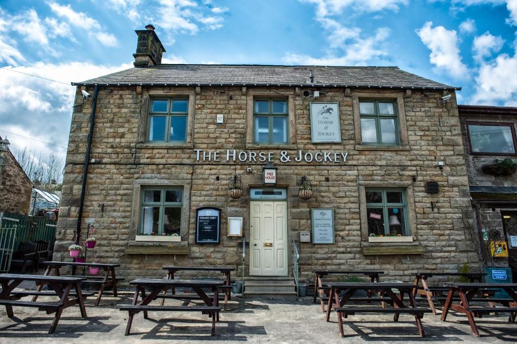 - un bâtiment en pierre avec des tables de pique-nique devant dans l'établissement The Horse and Jockey, à Tideswell