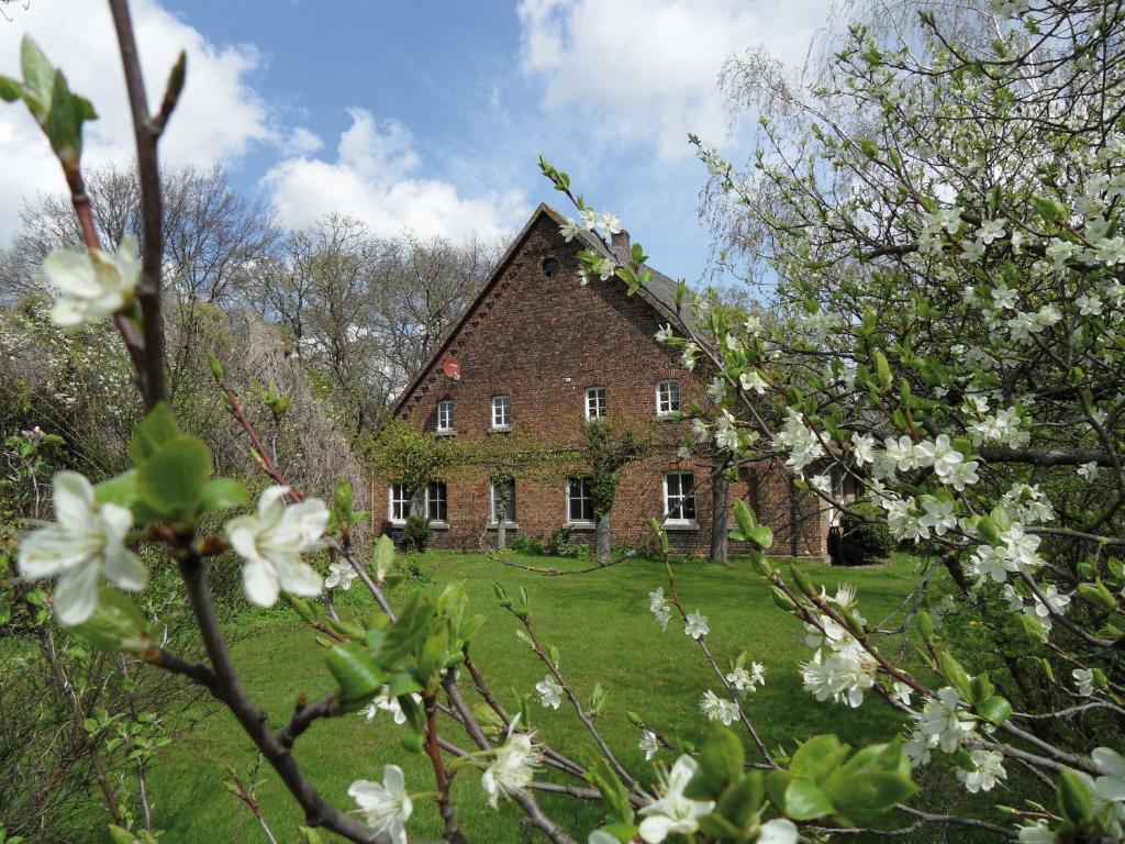 una vieja casa de ladrillo en un campo con flores blancas en Gästehof Brockum, altes Bauernhaus, großer Garten en Brockum