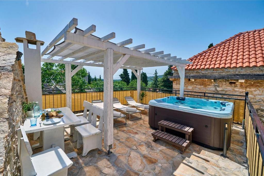 een patio met een hot tub en een houten pergola bij Villa Fortuna in Srednje Selo na Šolti