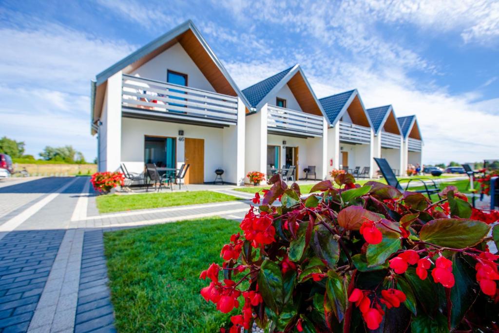 uma casa com flores vermelhas em frente em Molo Resort em Niechorze