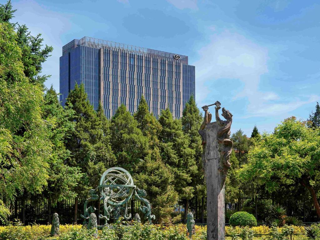 una statua in un parco con un edificio sullo sfondo di Sofitel Beijing Central a Pechino