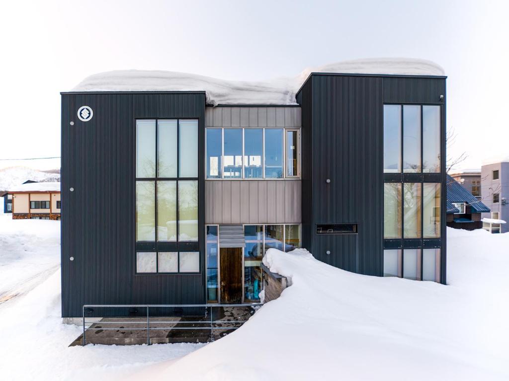 una casa con una fachada negra en la nieve en Sekka Ni Chalet en Niseko