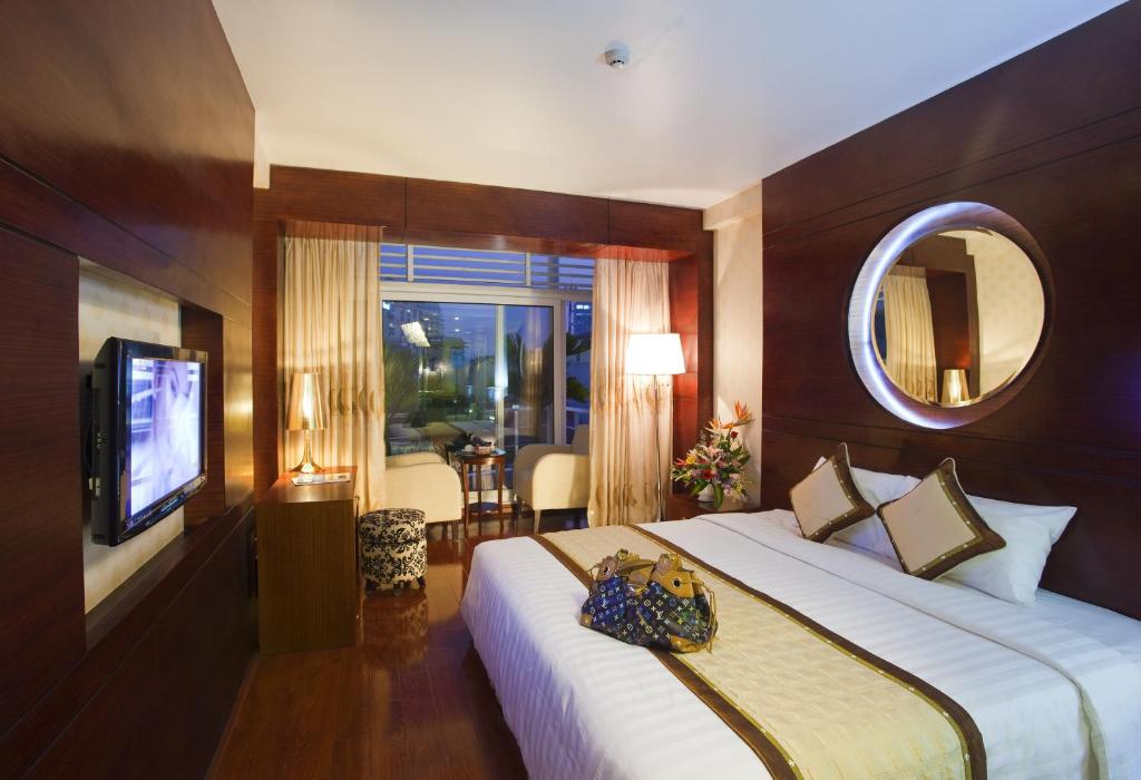 Cette chambre comprend un grand lit et un miroir. dans l'établissement Millennium Hanoi Hotel, à Hanoï