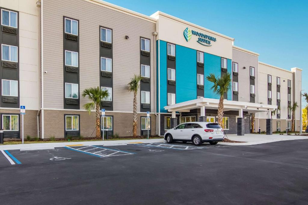 a car parked in a parking lot in front of a hotel at WoodSpring Suites Jacksonville Baymeadows in Deerwood Club