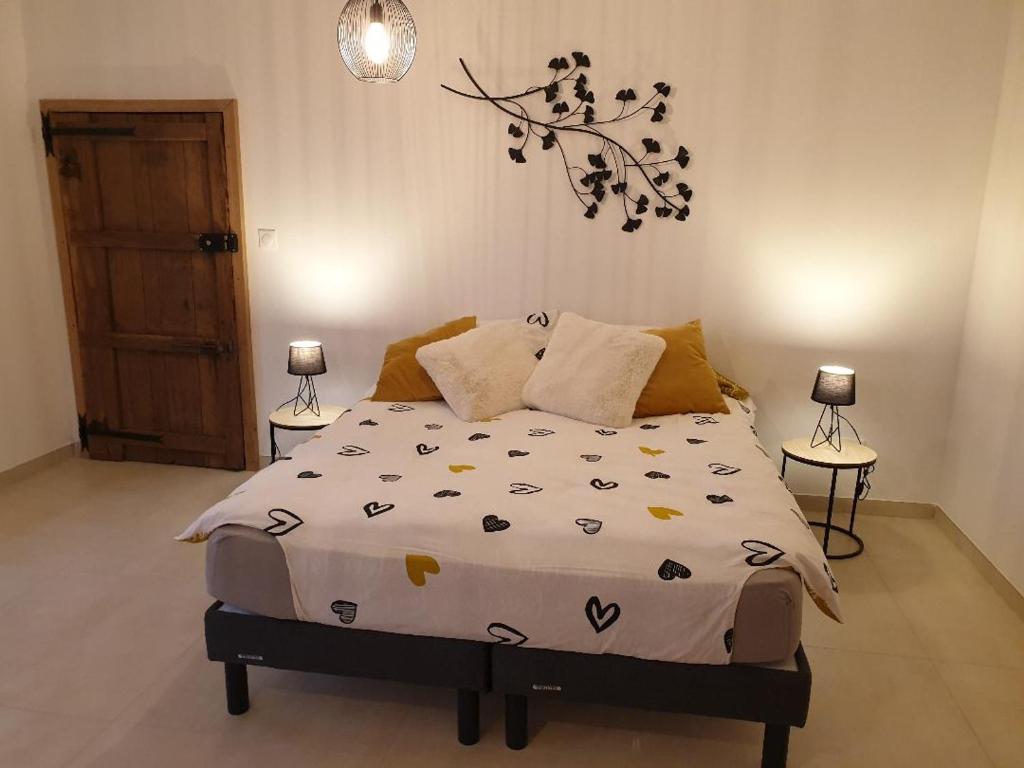 1 cama en un dormitorio con 2 lámparas en la pared en La Clef des Champs, en Potelle
