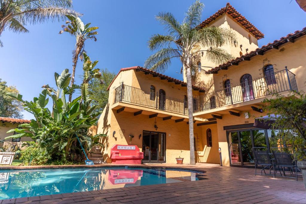 a house with a swimming pool and palm trees at Airport Tower Lodge in Kempton Park