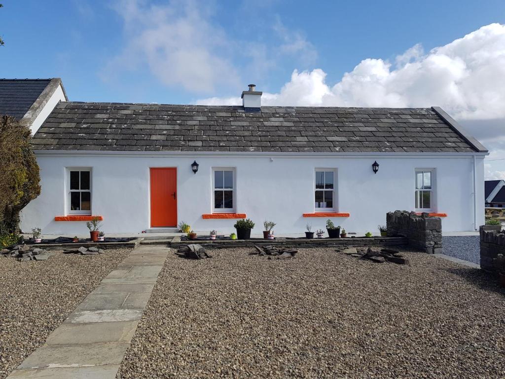 uma casa branca com uma porta vermelha em The Coral Cottage em Doolin