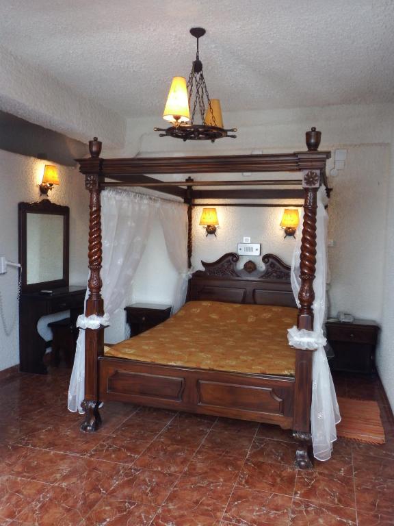 a bedroom with a wooden bed with a canopy at Hotel Porto Perissa in Perissa