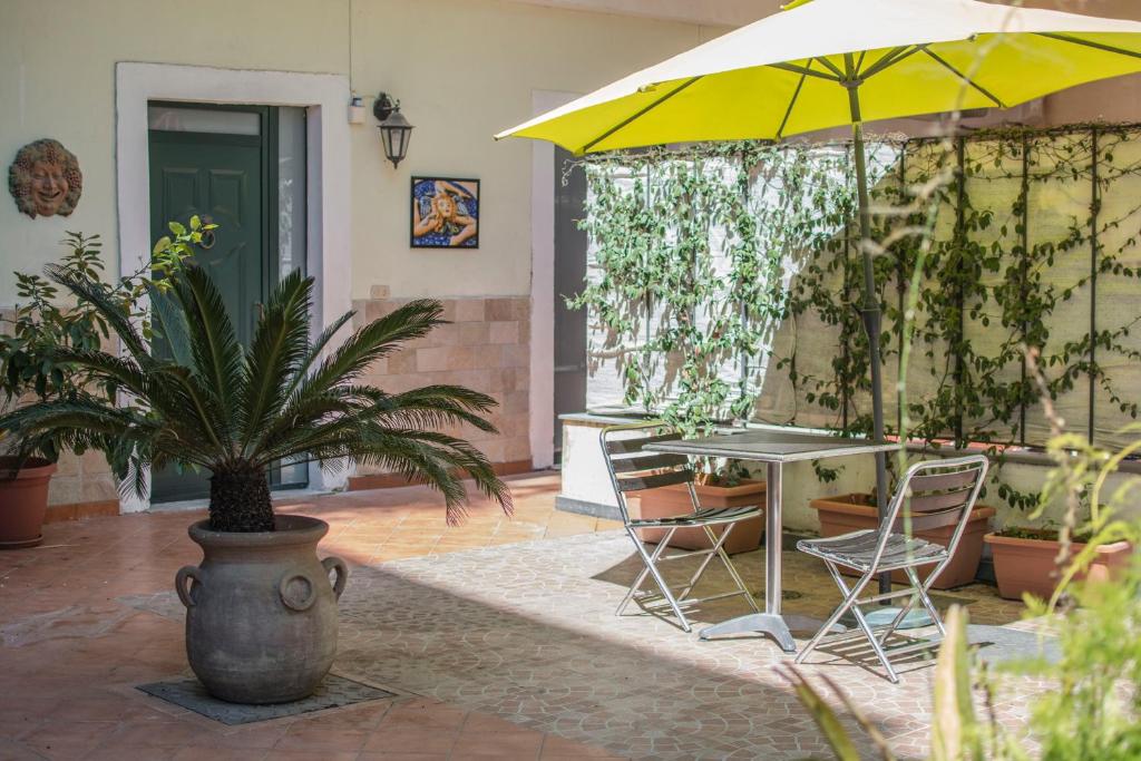un patio con una mesa y una sombrilla amarilla en Callas Room Opera, en Catania