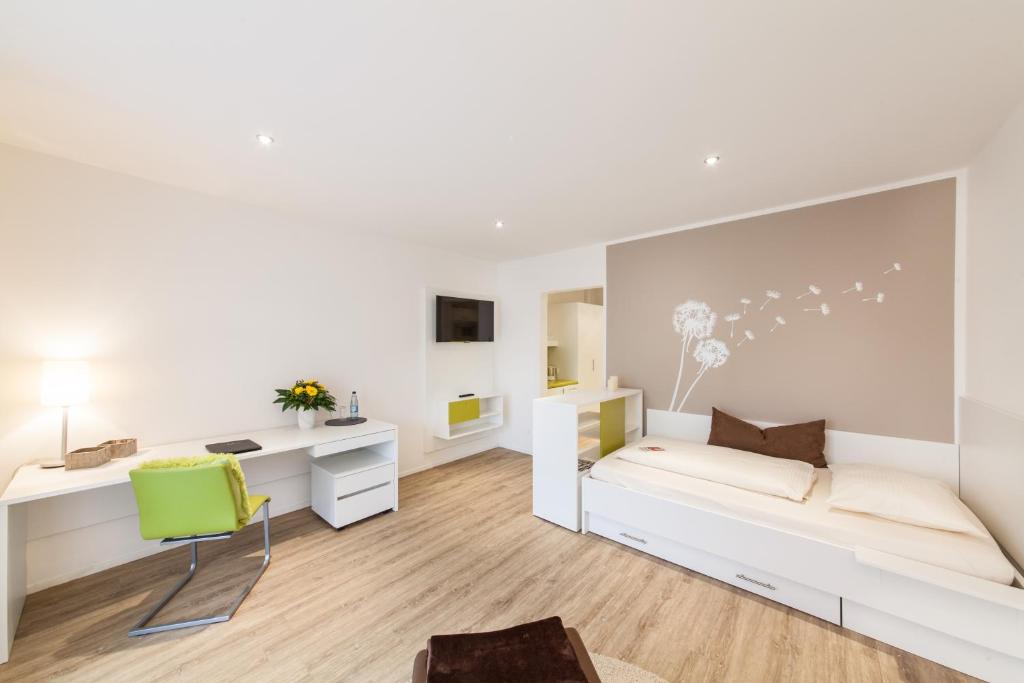 a bedroom with white furniture and a green chair at acora Fürth Living the City- Apartments in Fürth