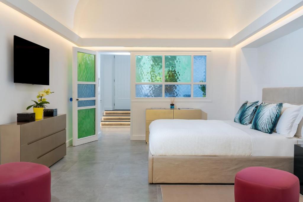 a bedroom with a bed and a tv and some pink chairs at Civico 7 in Capri