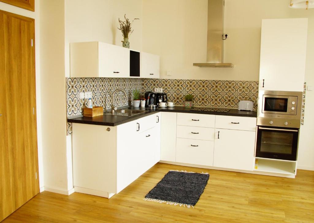 a kitchen with white cabinets and a black counter top at Apartmány u komína in Terezín