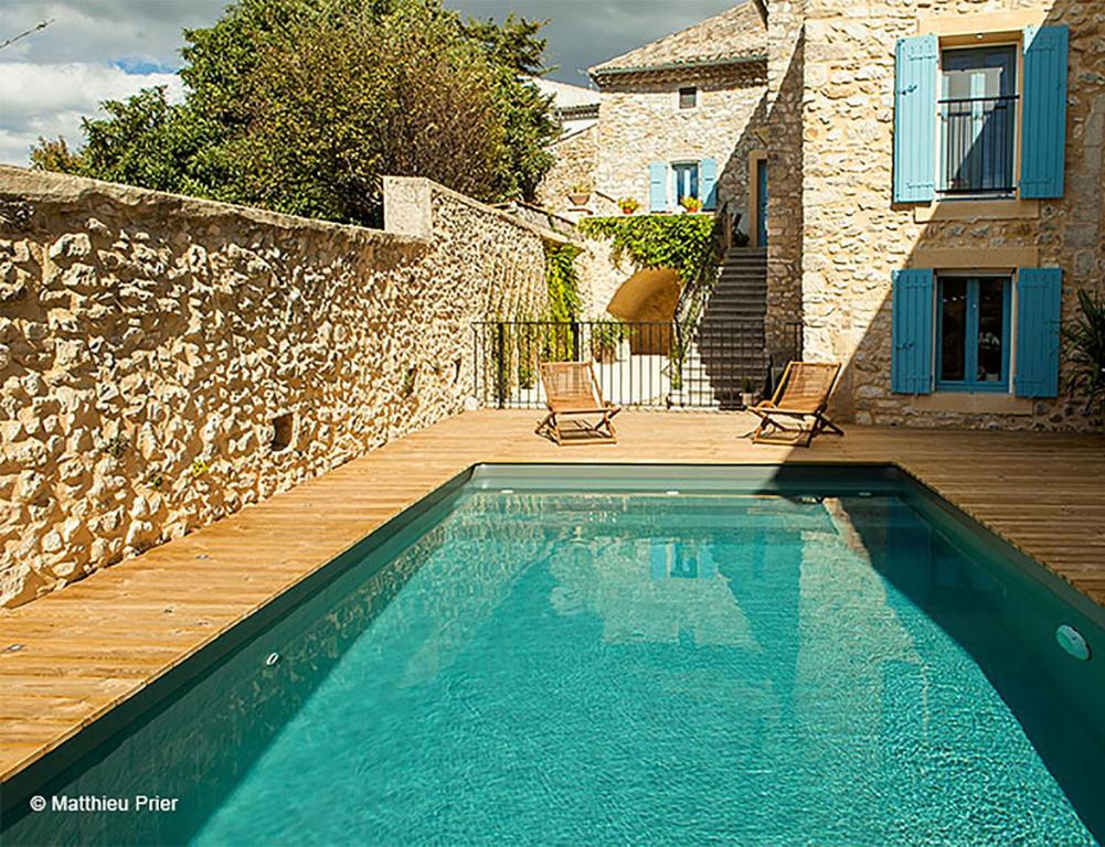 a swimming pool with a wooden deck and a house at Clarberg - B&B in Saint-André-de-Roquepertuis