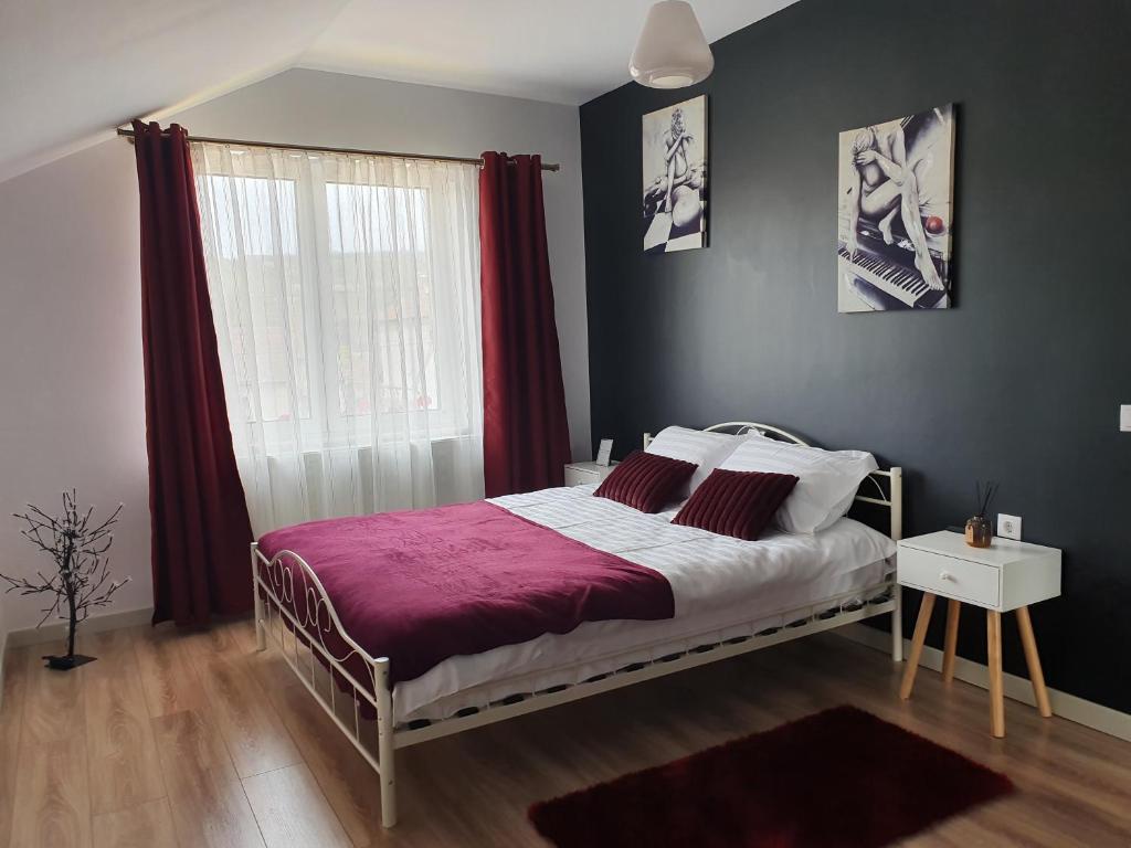 a bedroom with a large bed with red curtains at Edith's House in Turda