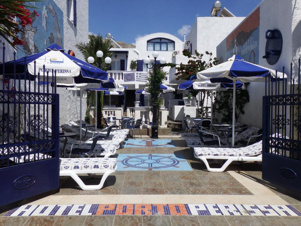a patio with blue and white umbrellas and chairs at Hotel Porto Perissa in Perissa