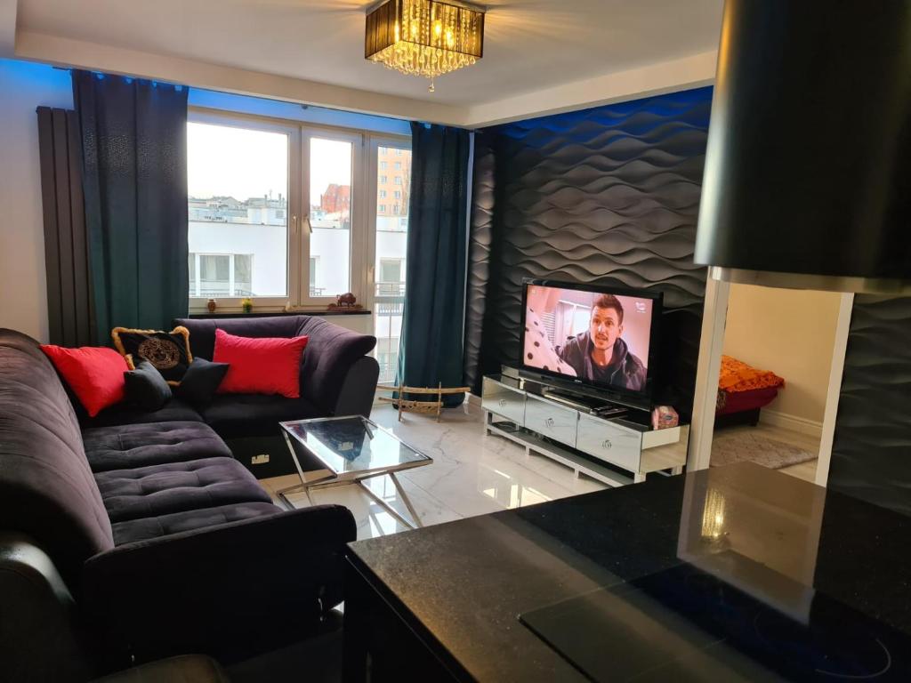 uma sala de estar com um sofá e uma televisão em Apartament Przy Starym Mieście em Szczecin
