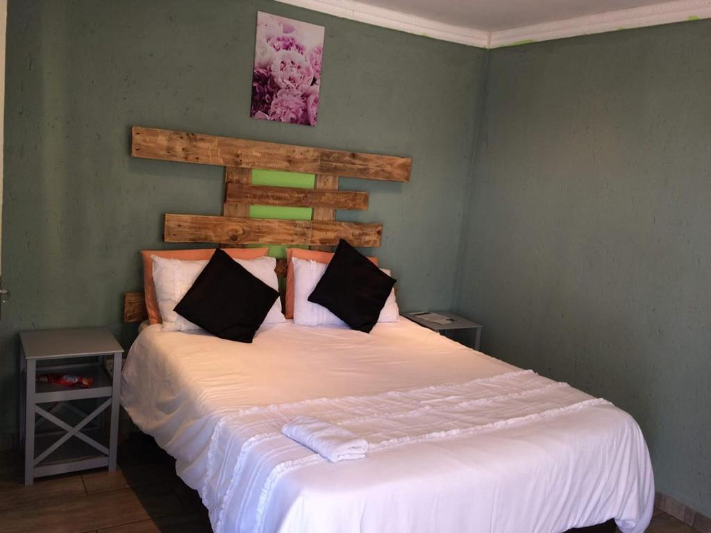 a bedroom with a large bed with white sheets at Lapa la Bakgatlha in Soweto