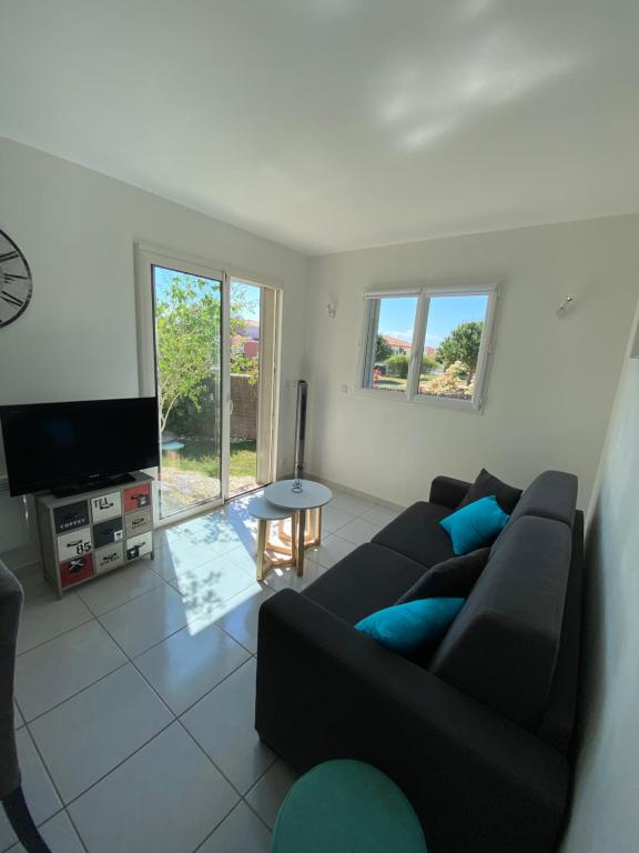 a living room with a black couch and a tv at Cocooning in Torreilles
