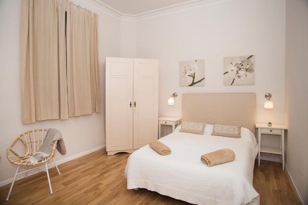 um quarto branco com uma cama e uma cadeira em Mai & Maud Ronda Apartment em Barcelona