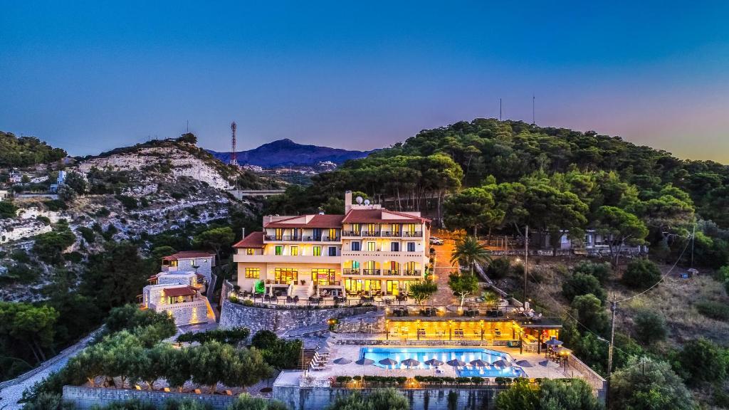 a large building on a hill with a swimming pool at Forest Park Hotel in Rethymno