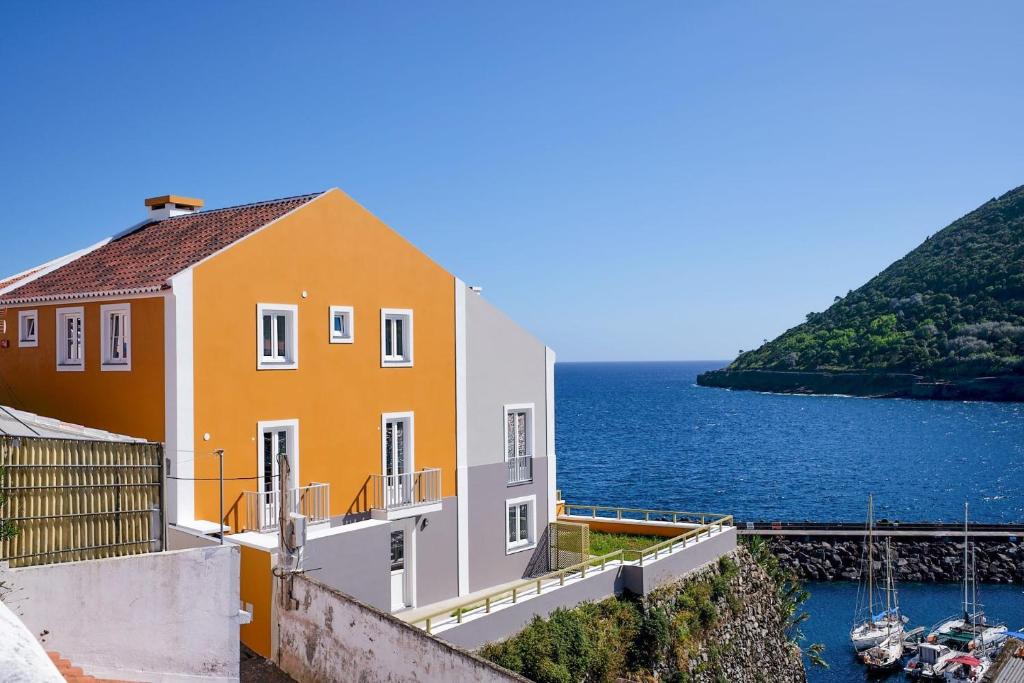 un bâtiment jaune et blanc à côté d'une masse d'eau dans l'établissement Mid-Atlantic Boutique Hostel, à Angra do Heroísmo