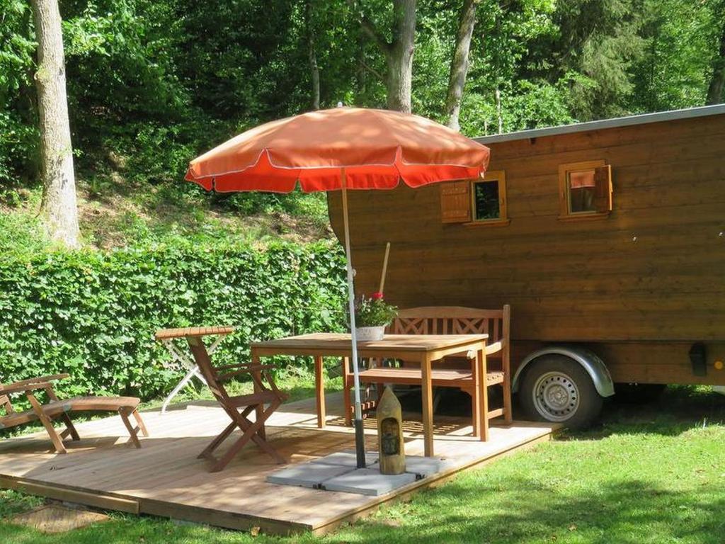 a table with an umbrella next to a trailer at Bienenwagen der Naturheilpraxis Melchger in Wildberg