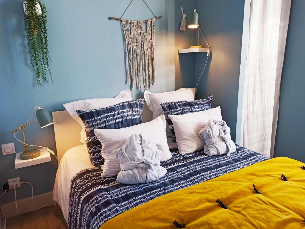 - une chambre bleue avec un lit et des oreillers blancs dans l'établissement By Gwen - le Jaurès, à Arles