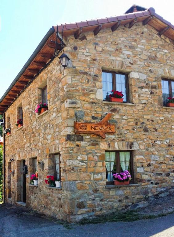 a stone building with windows and flowers on it at Casa Rural Nevada in Horcadas