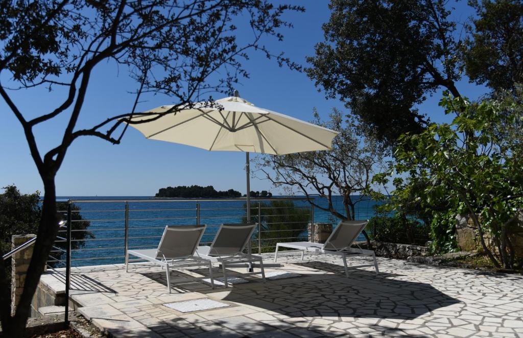 een patio met stoelen en een parasol naast het water bij Buric House - Apartments Klasik and Studio Mini in Rovinj