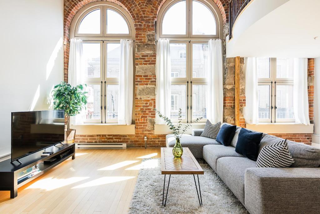uma sala de estar com um sofá e uma parede de tijolos em Les Lofts St Jean em Cidade de Quebec
