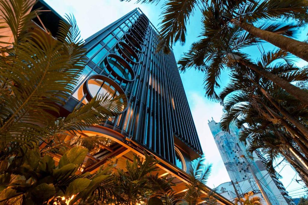 un grand bâtiment avec des palmiers devant lui dans l'établissement Hotel Marquee Medellín, à Medellín