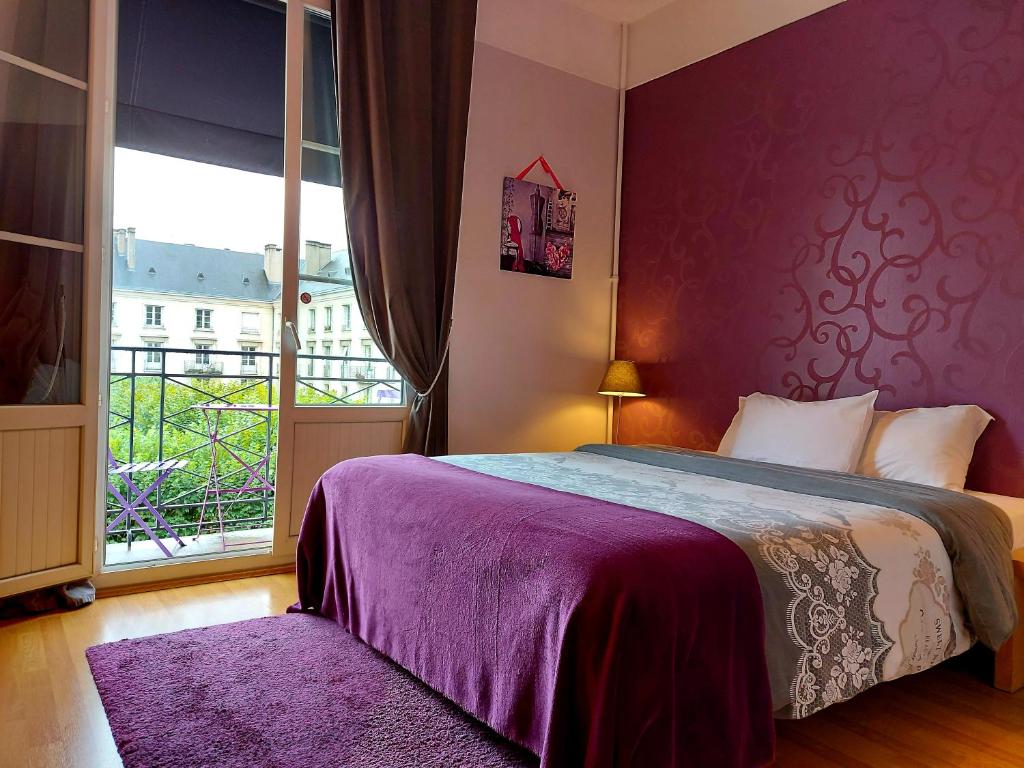 a bedroom with a bed with a purple wall at Hotel Mondial in Tours