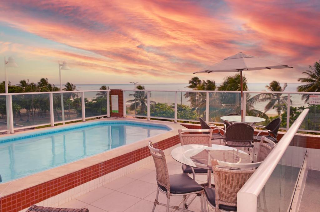 a balcony with a pool and tables and chairs at Nord Easy Ondas do Atlantico in João Pessoa