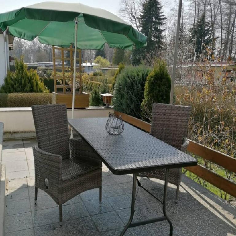 ein Tisch und Stühle mit einem grünen Sonnenschirm in der Unterkunft Am Schwielochsee 2 in Speichrow