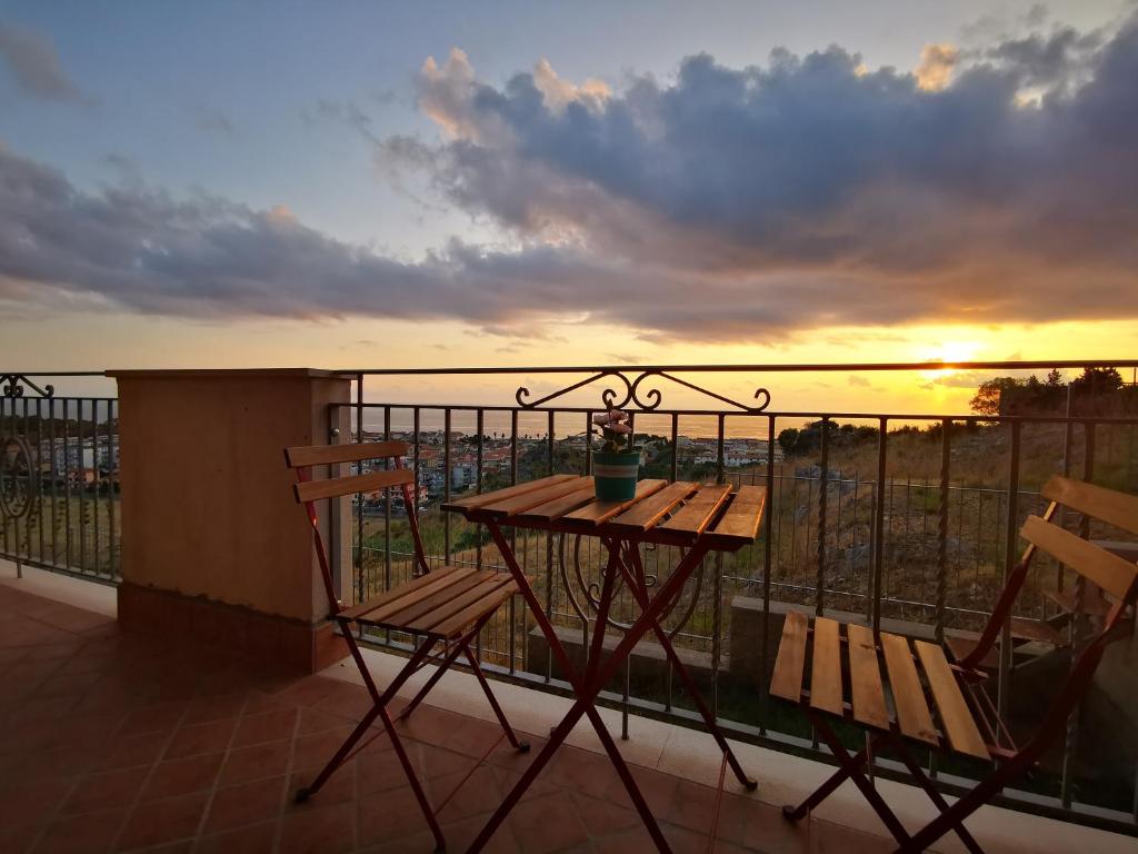 una mesa y sillas en un balcón con puesta de sol en La Dolce Dimora, en Praia a Mare