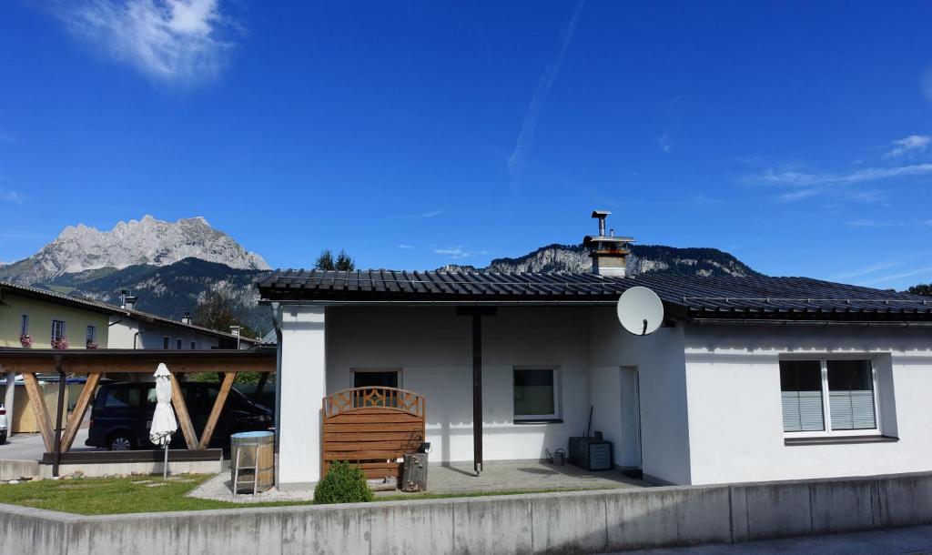 a white house with a mountain in the background at Bungalow Baloo Ferienhaus in Sankt Johann in Tirol