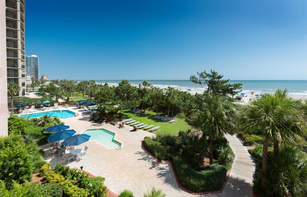 an aerial view of a resort with a pool and the beach at Beach Colony Resort in Myrtle Beach