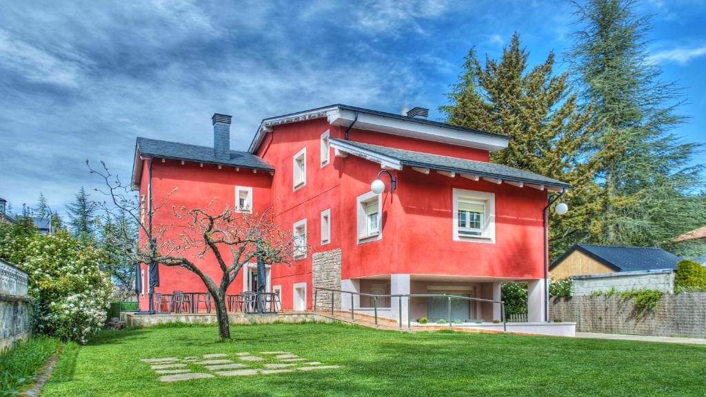 une maison rouge avec une cour verdoyante devant elle dans l'établissement PURA VIDA PIRINEOS, à Jaca