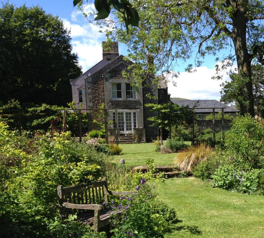 una vecchia casa in pietra con una panchina in giardino di Ingram House Bed & Breakfast ad Alnwick