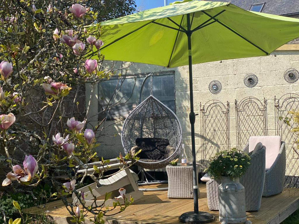 a green umbrella on a table with chairs and a bird cage at The Sail Loft in Kingsbridge
