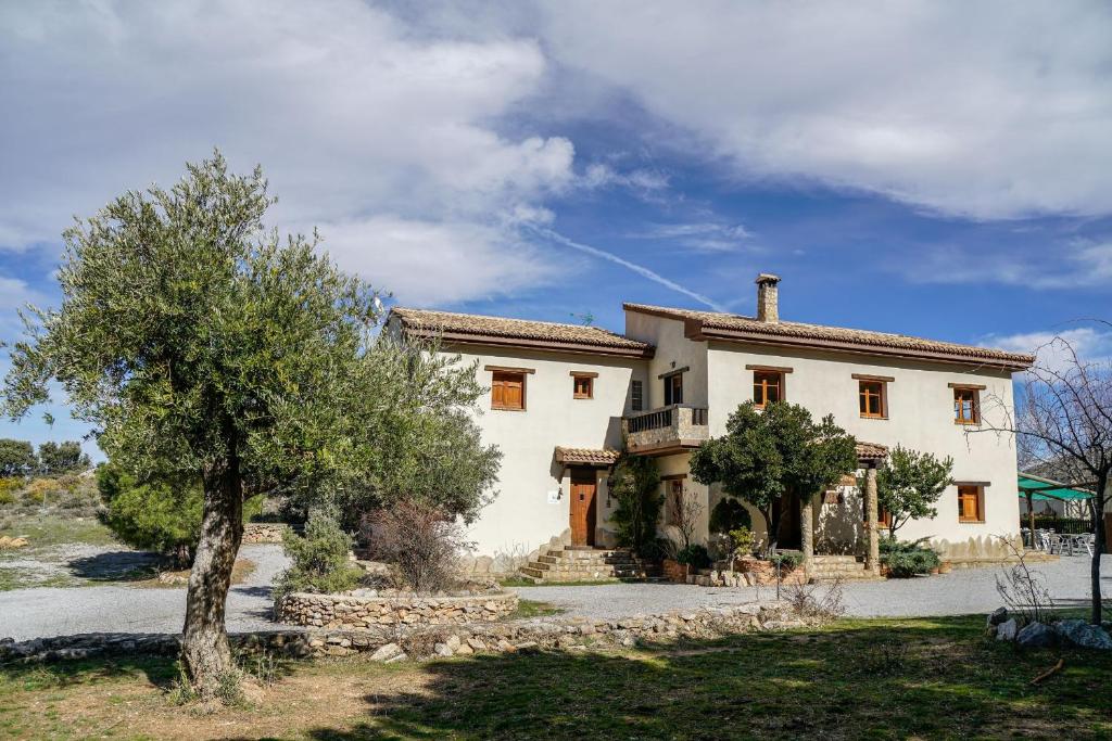 una gran casa blanca con un árbol delante en Hotel Rural Fuente La Teja, en Güéjar-Sierra